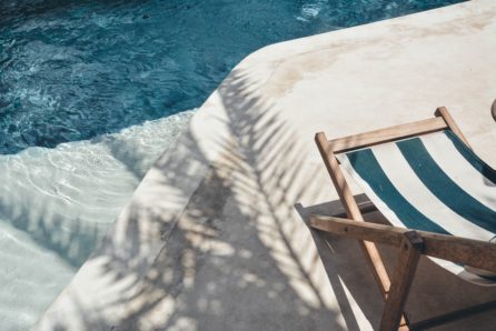 Transat en bois assise tissu rayée turquoise et blanc en bord de piscine